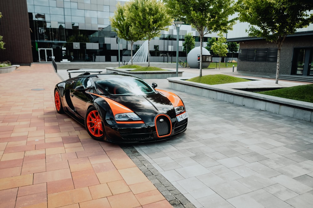 a black and orange bugatti parked in front of a building