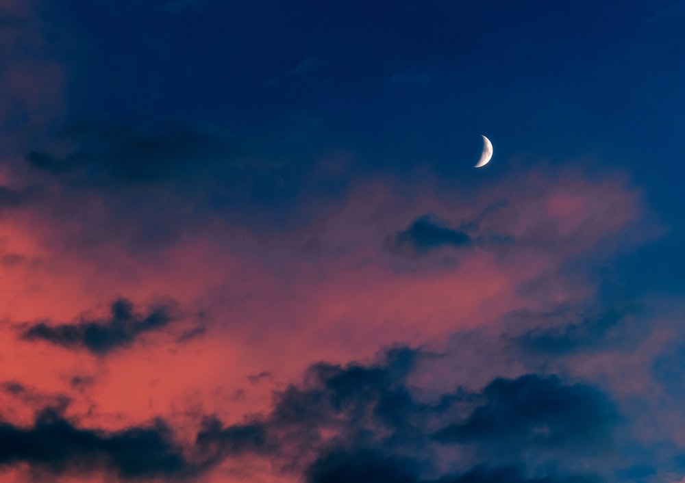 Une demi-lune est vue dans le ciel au coucher du soleil