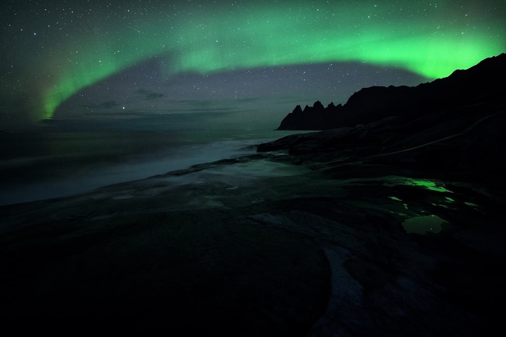 a green and black aurora over a body of water