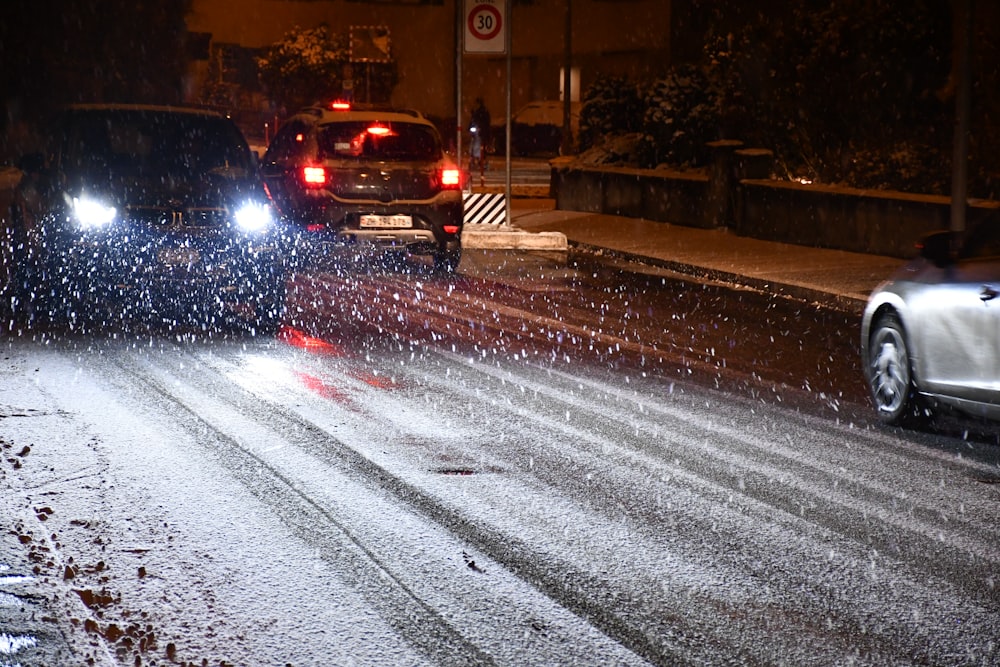 a couple of cars driving down a snow covered road