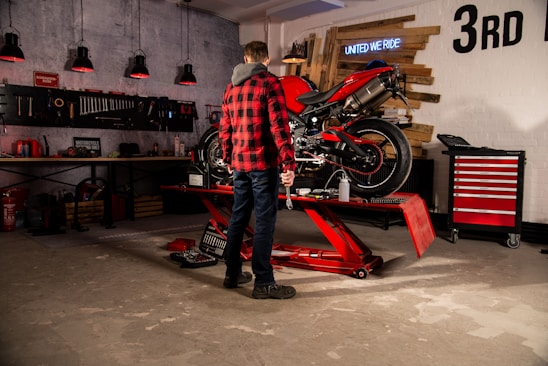 A skilled mechanic working on a motorcycle engine in a well-equipped workshop.