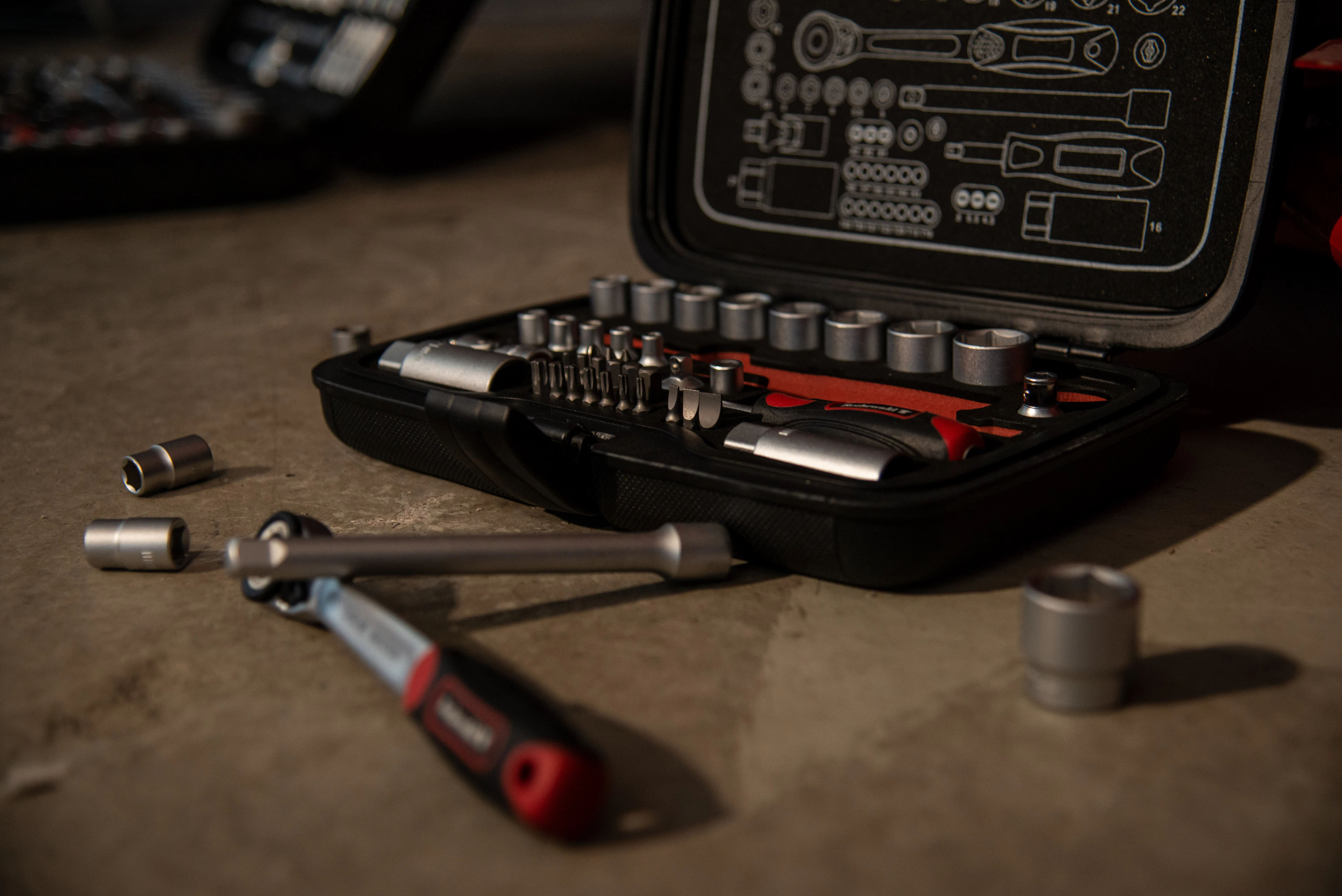 An open socket set case with a ratchet and loose sockets on a workbench