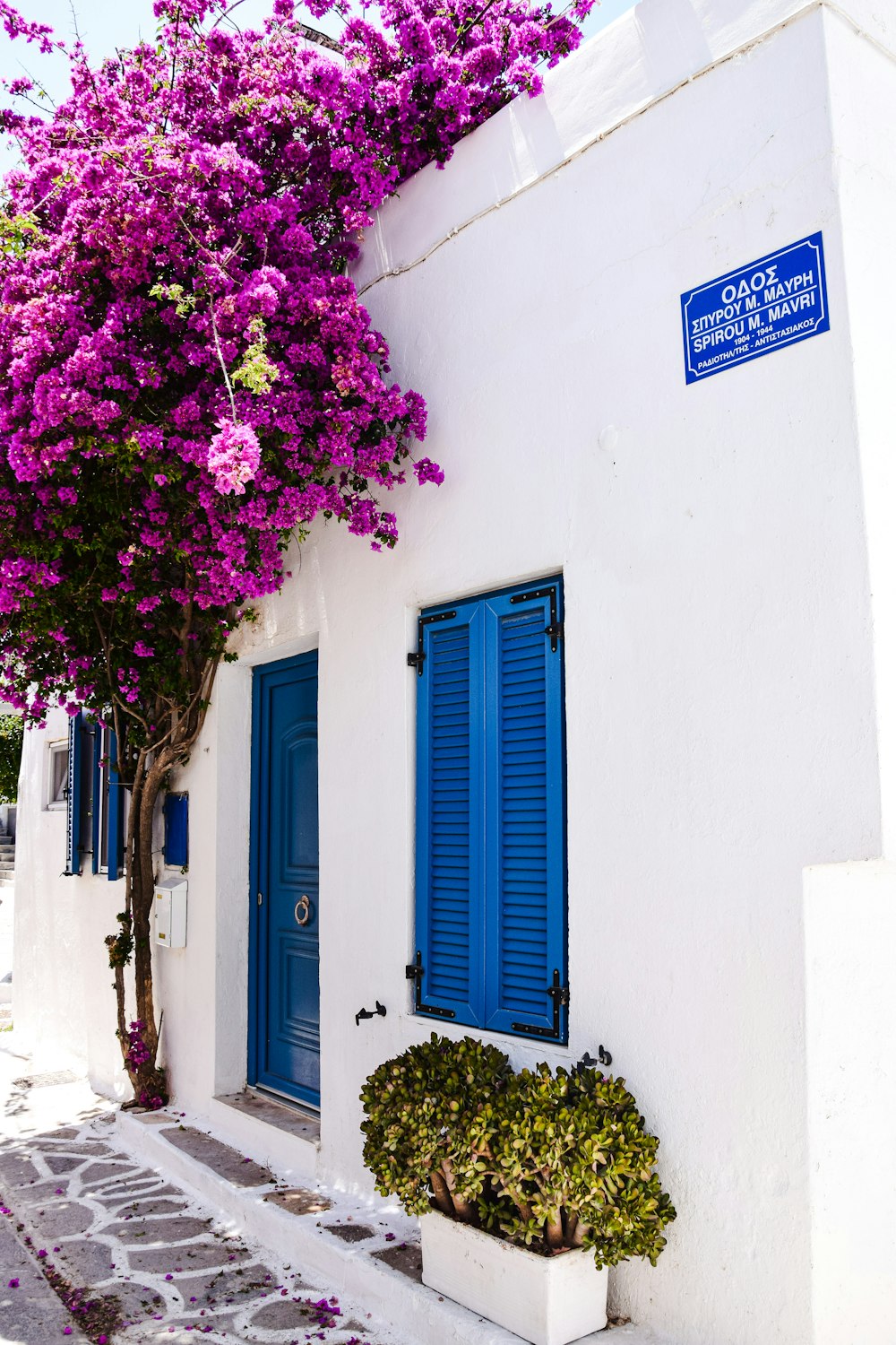 a white building with blue shutters and a blue door