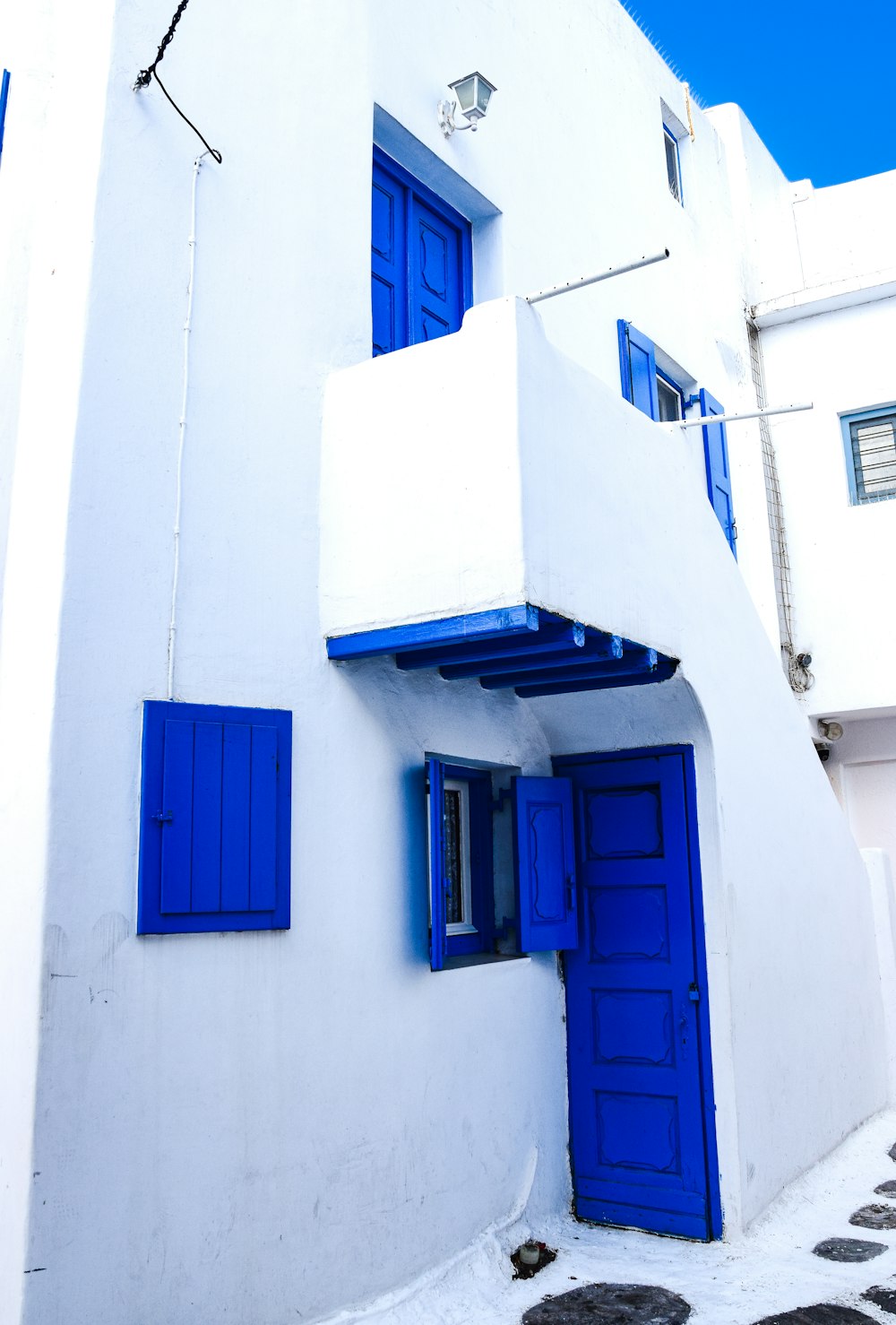 a white building with blue shutters and a blue door