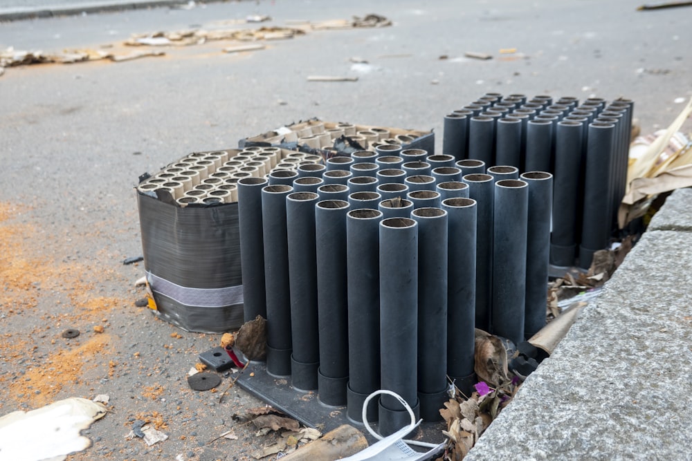 a pile of black pipes sitting on the side of a road