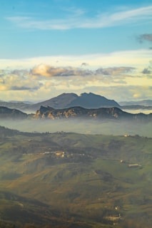 Wide view of emerald hills and distant misty peaks.