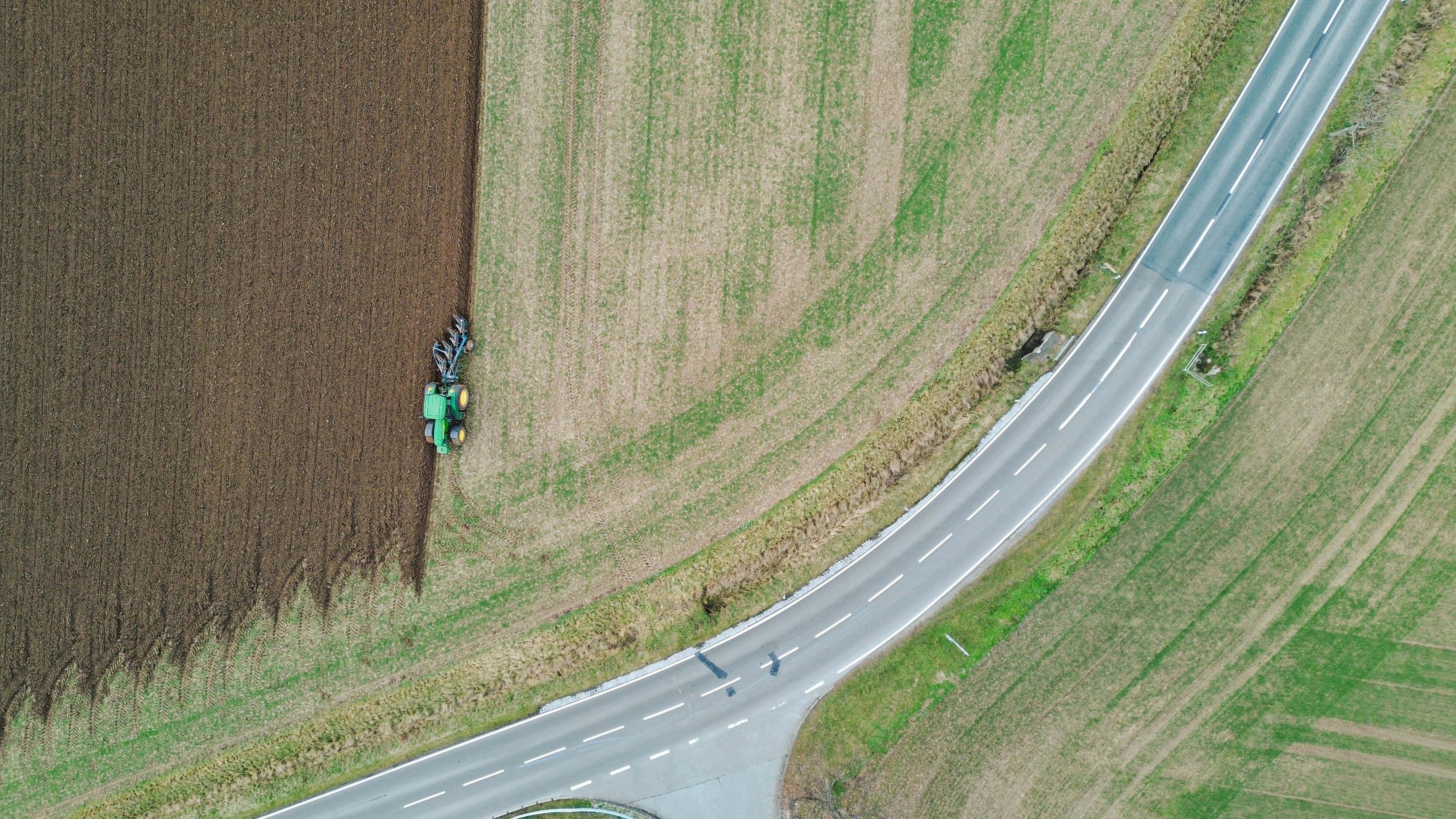 an aerial view of a country road and a tractor