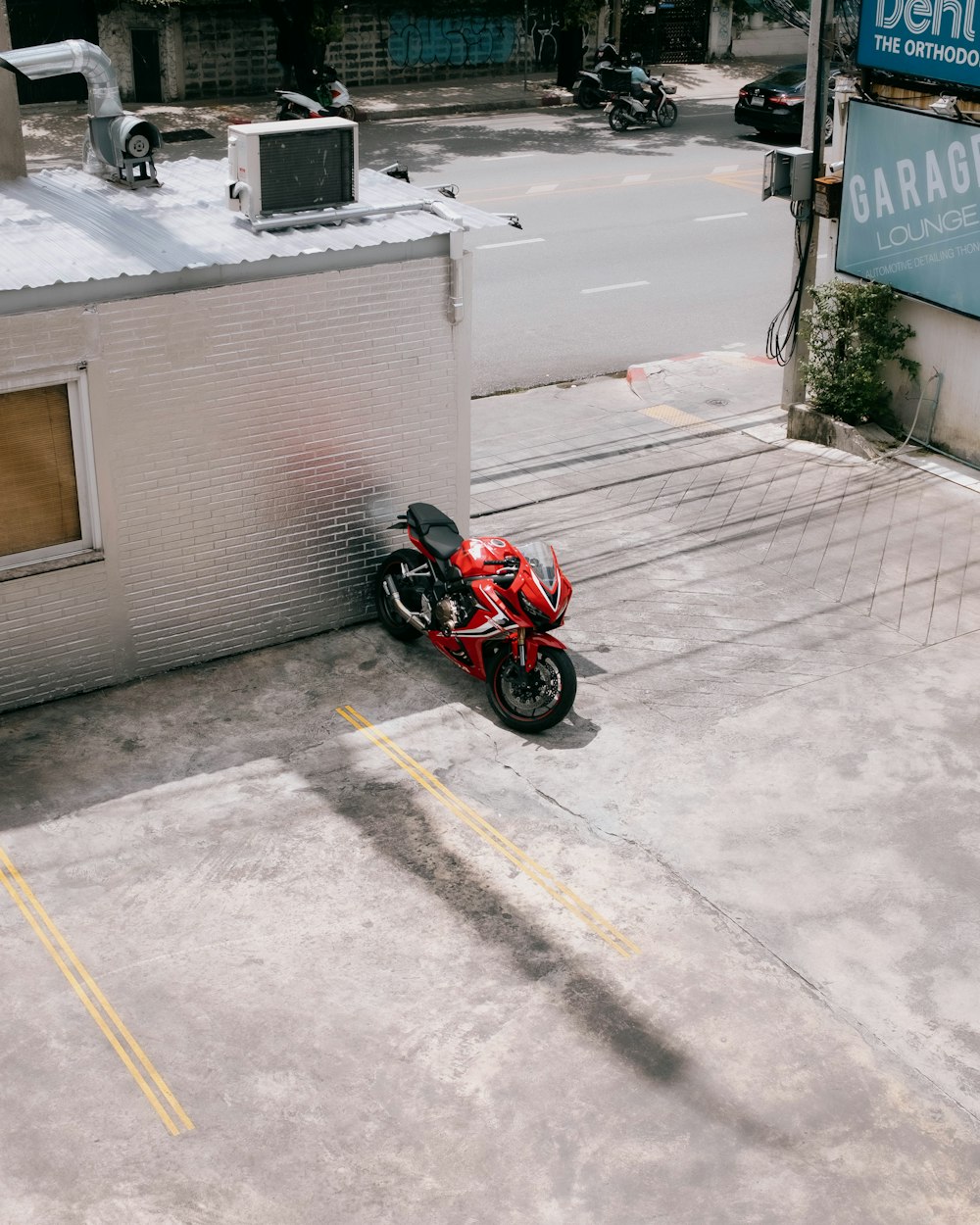 a red motorcycle parked in a parking lot next to a building