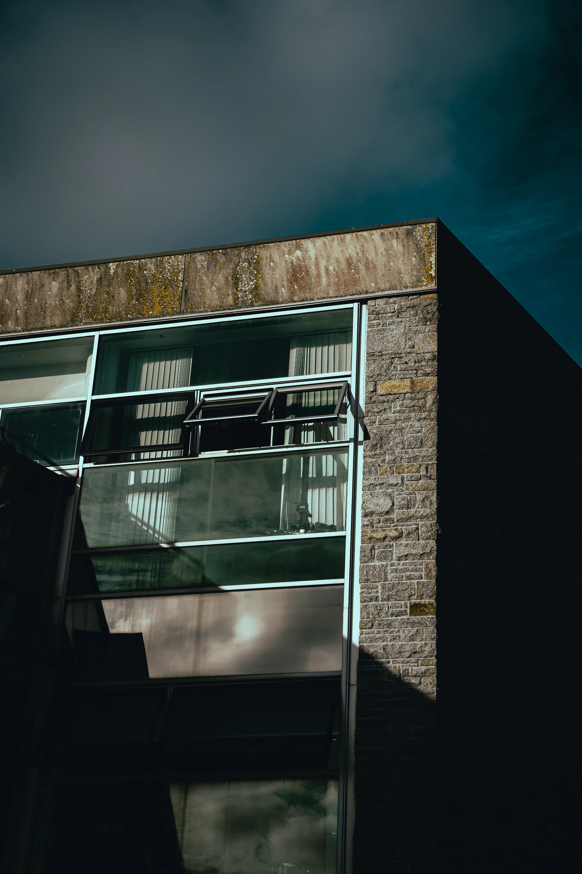 Modern architectural facade with clean lines and large glass windows reflecting the sky