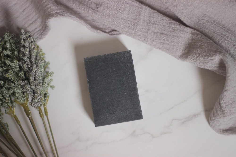 a gray book sitting on top of a table next to flowers