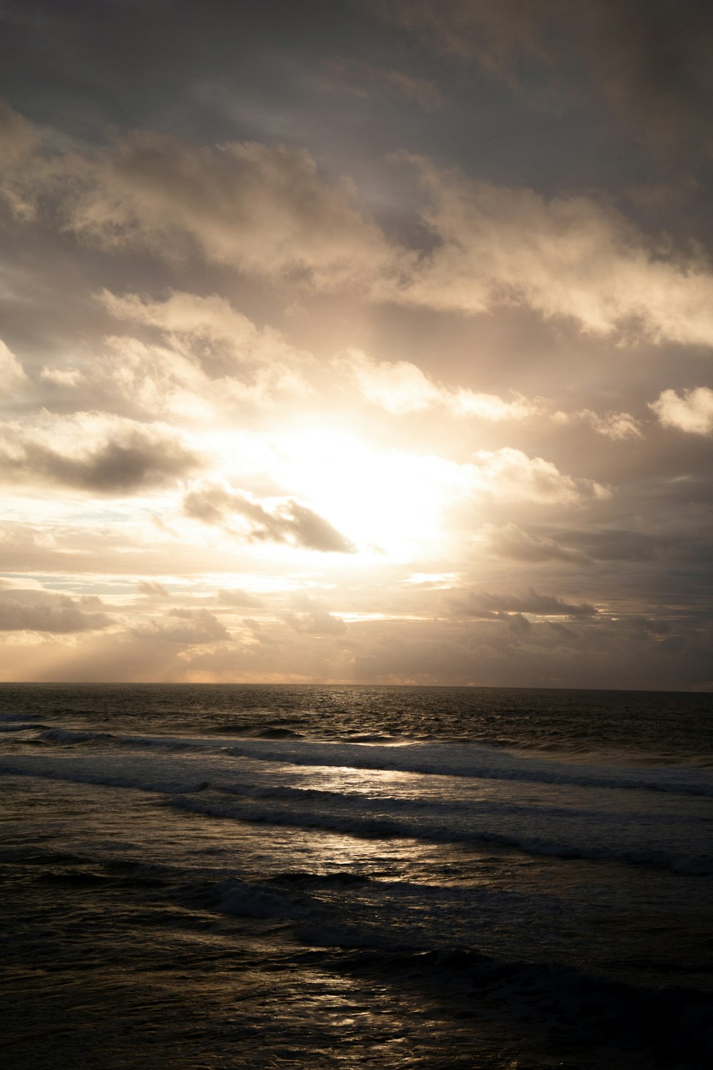 太陽が海の上の雲を通して輝いています