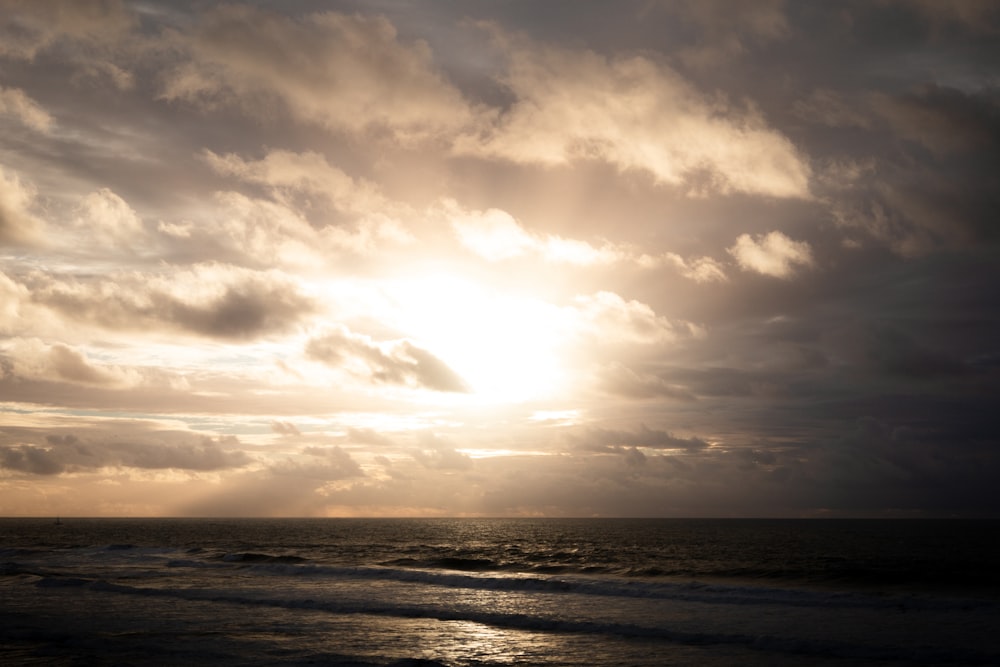 the sun is shining through the clouds over the ocean