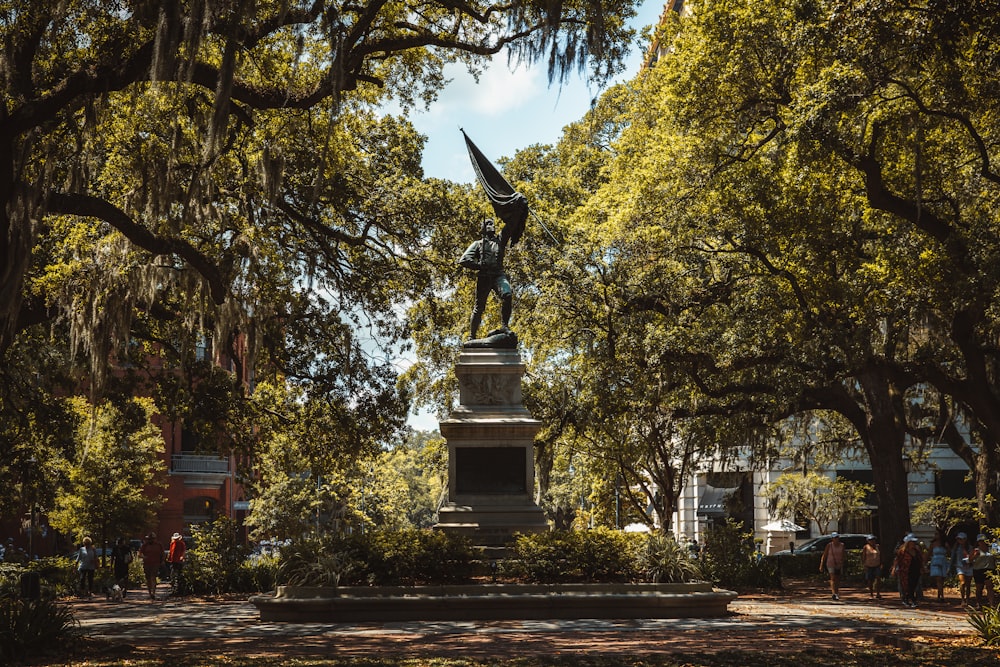 a statue in a park surrounded by trees