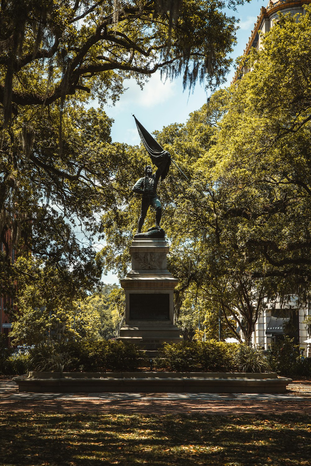 a statue of a man holding a flag in a park