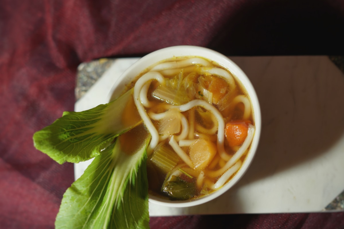 a bowl of soup with noodles, carrots and celery