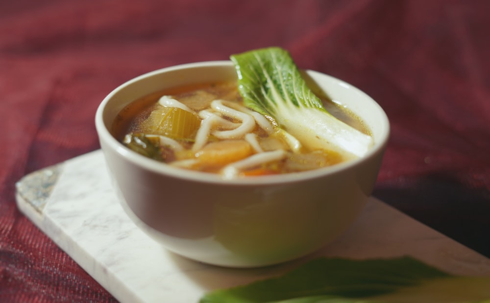 a bowl of soup with noodles, carrots and celery