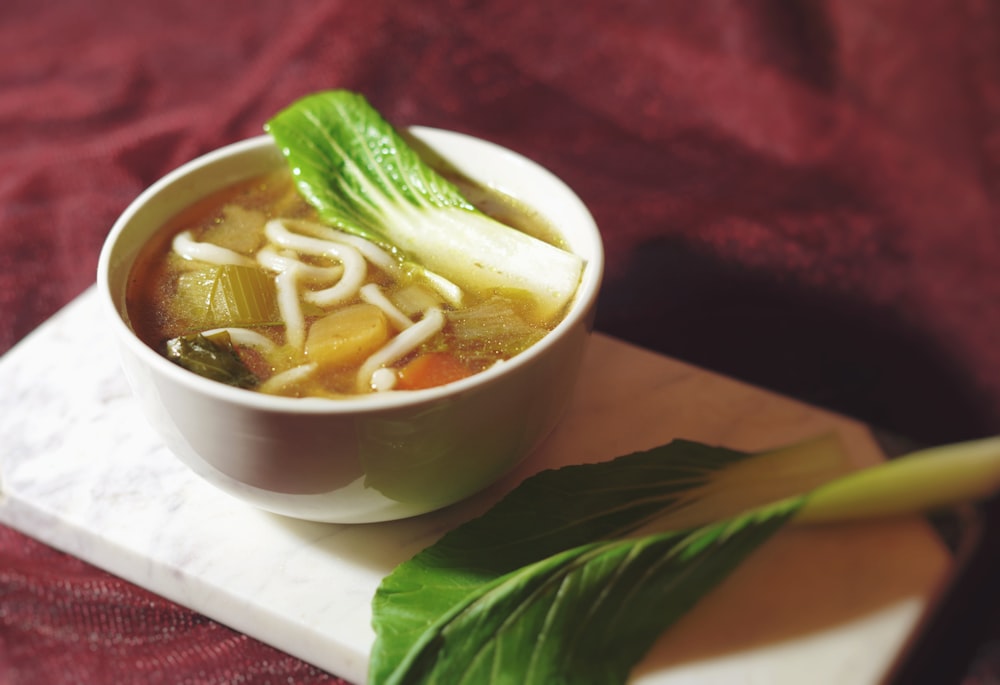 a white bowl filled with soup and vegetables