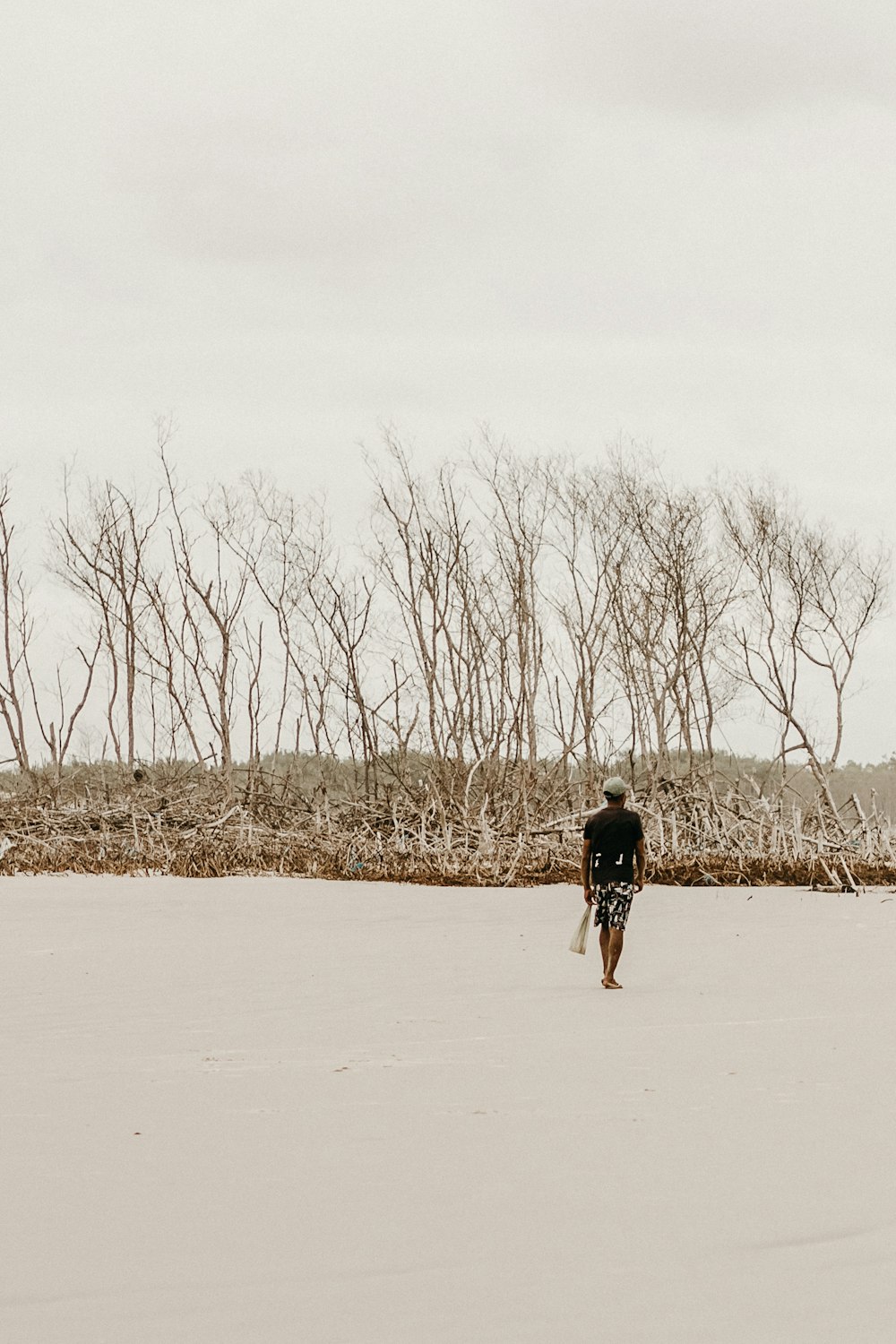 a man riding a surfboard across a sandy beach