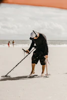 A treasure hunter scanning rocky terrain at sunset with a metal detector