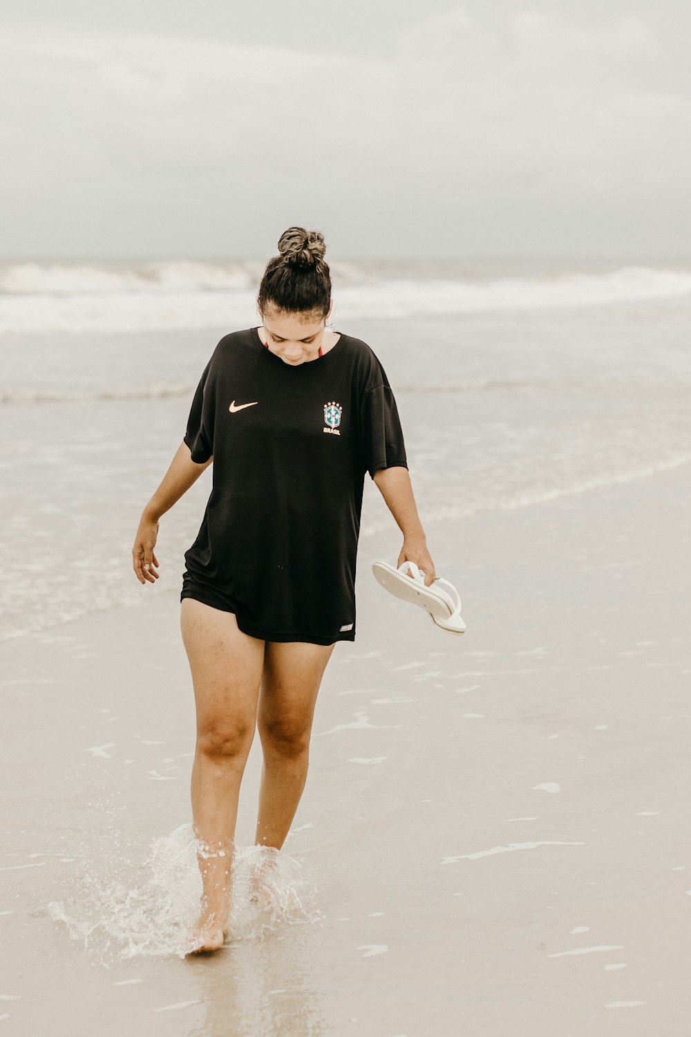 a woman walking on the beach with a frisbee