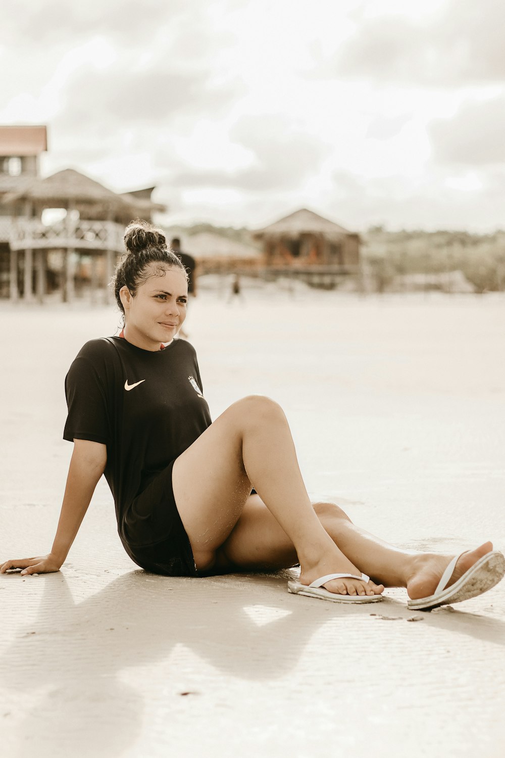 a woman sitting on the beach with her legs crossed