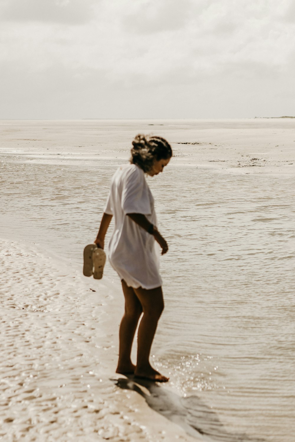 a woman standing on a beach next to a body of water