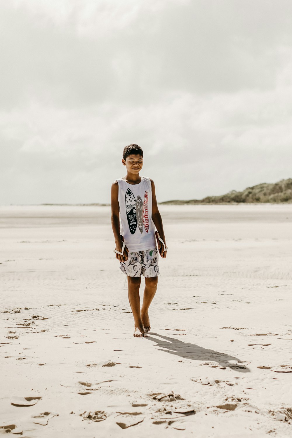 a man walking across a sandy beach next to the ocean