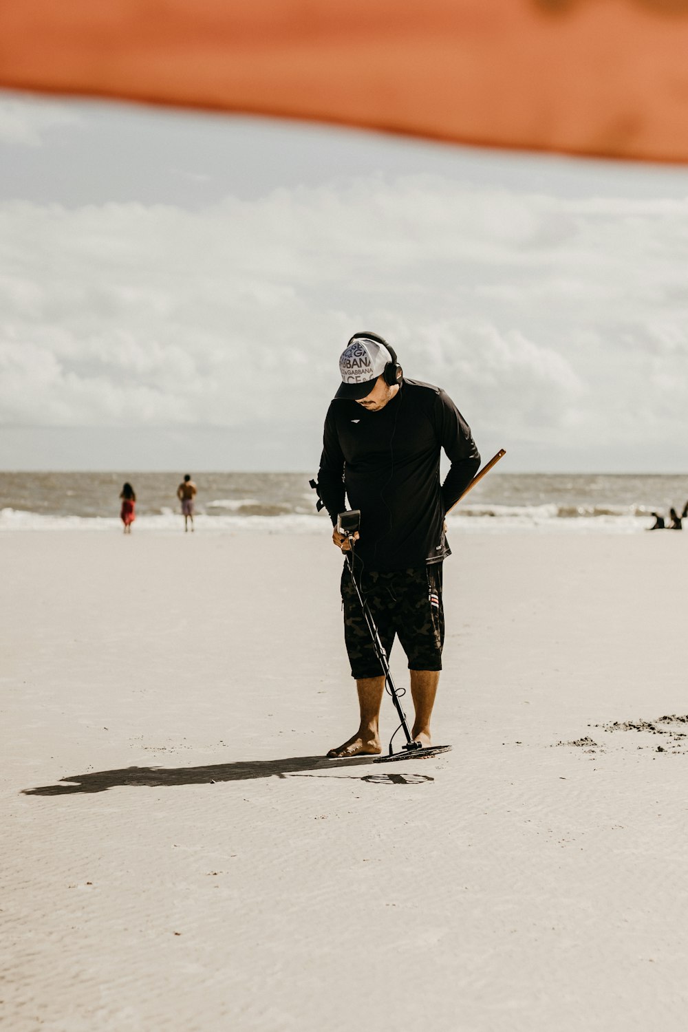 a man standing on a beach holding a baseball bat