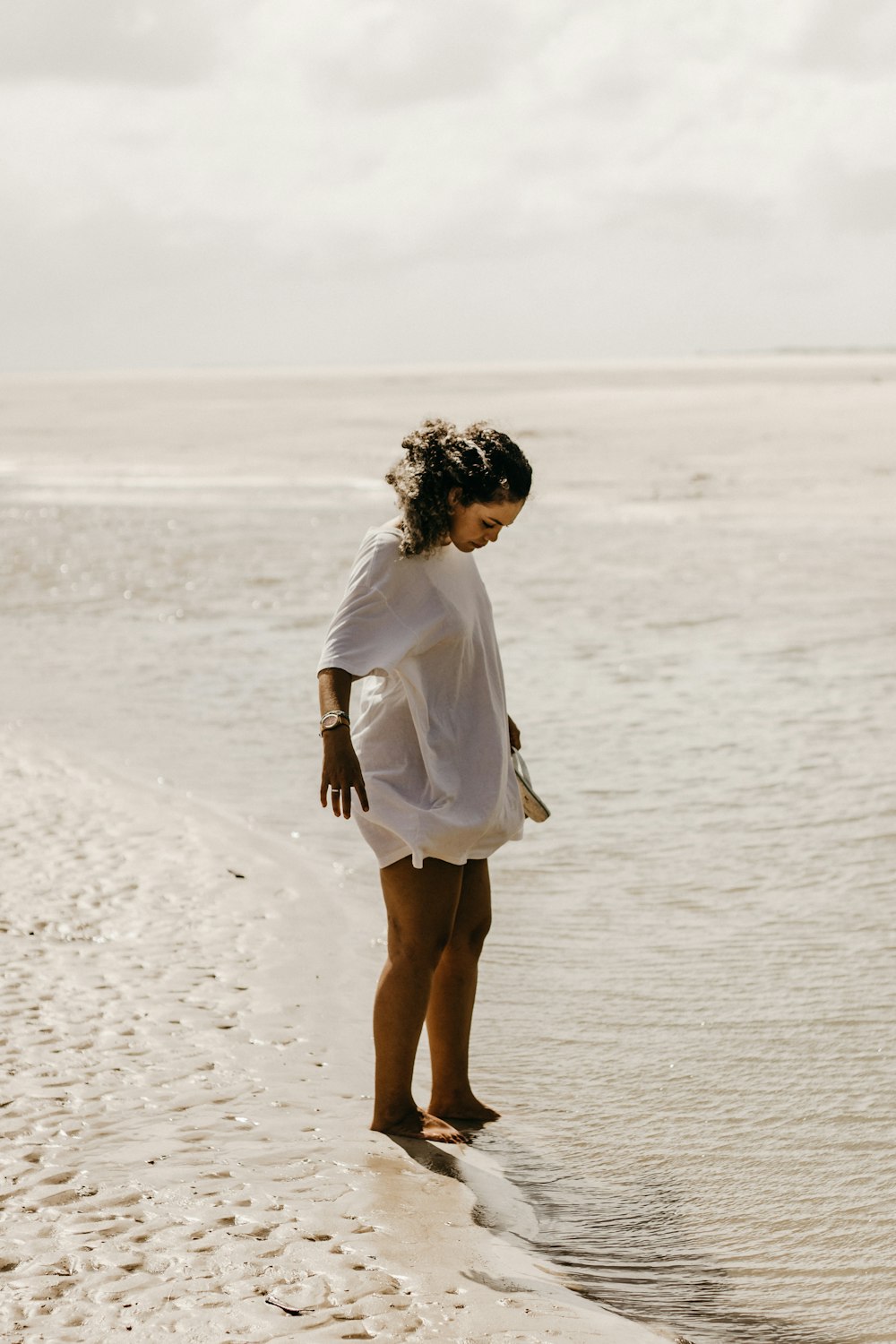 a woman standing on a beach next to the ocean