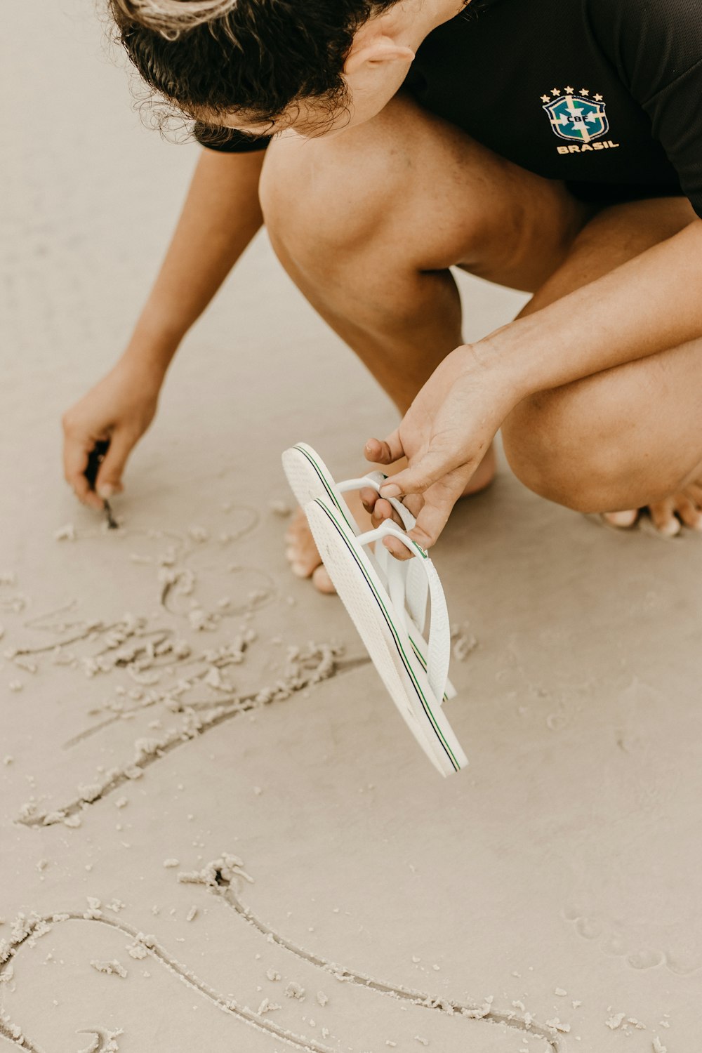 a person kneeling down on a beach tying a shoe