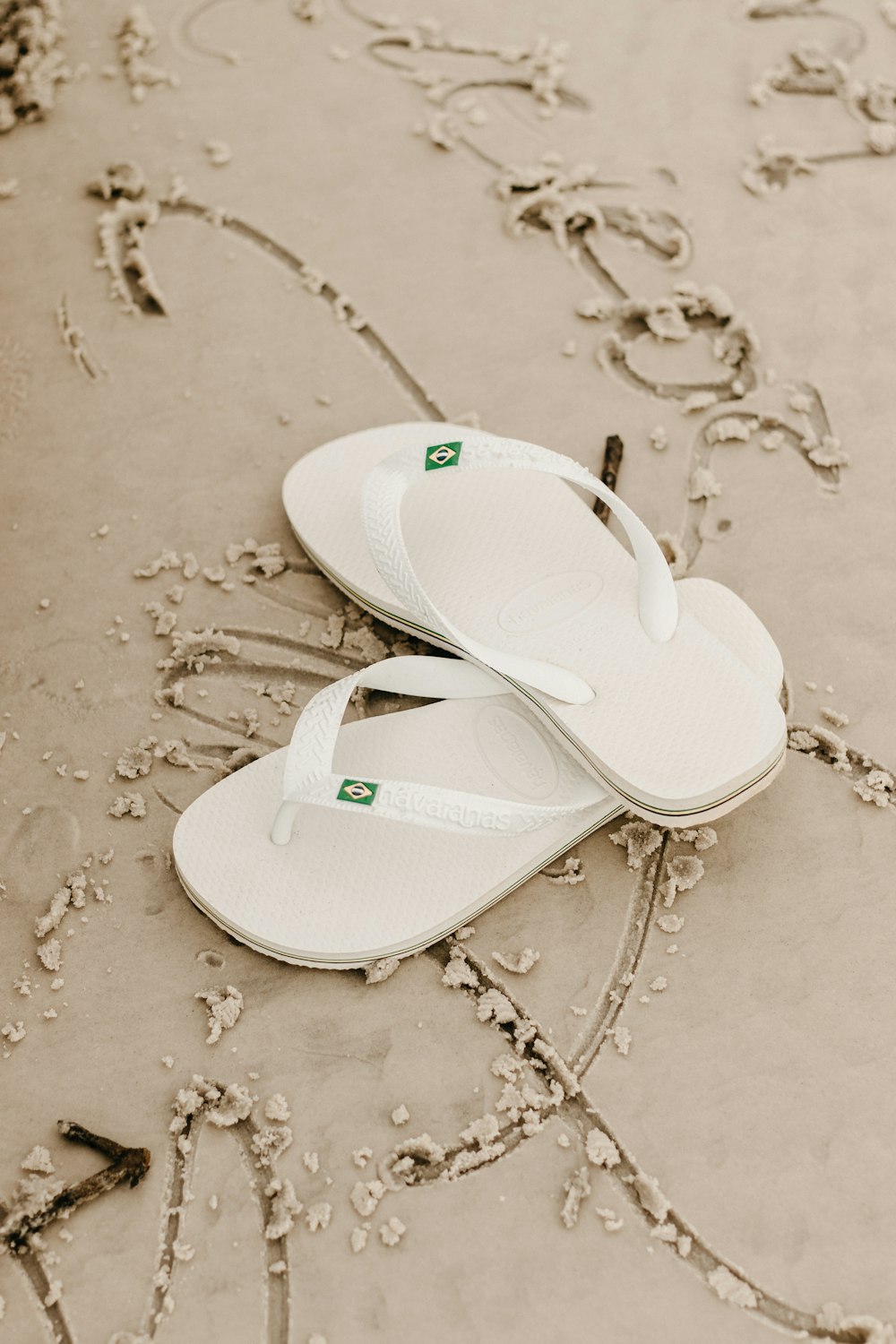 a pair of white slippers laying on top of a beach