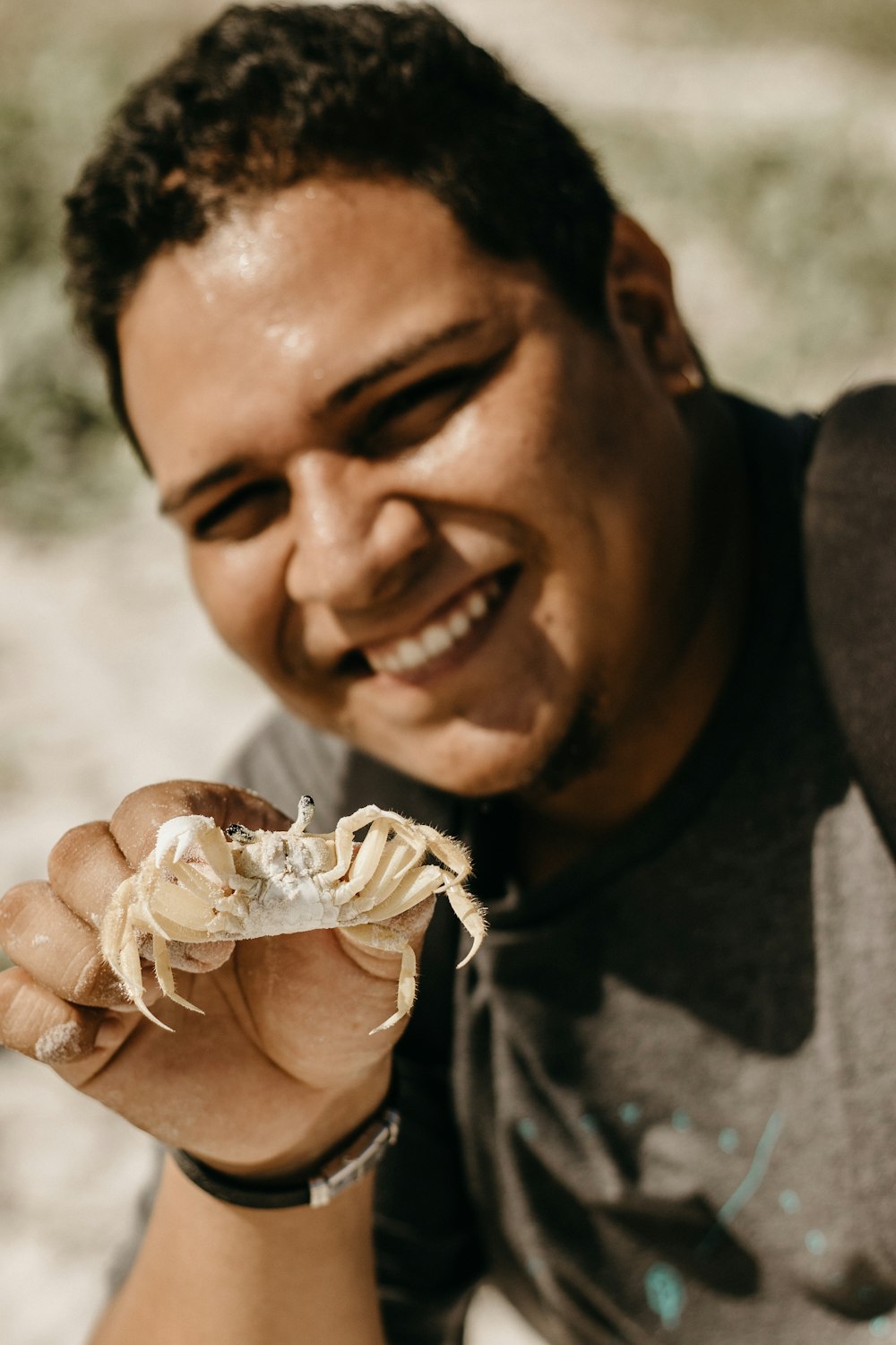 a smiling man holding a crab in his hand