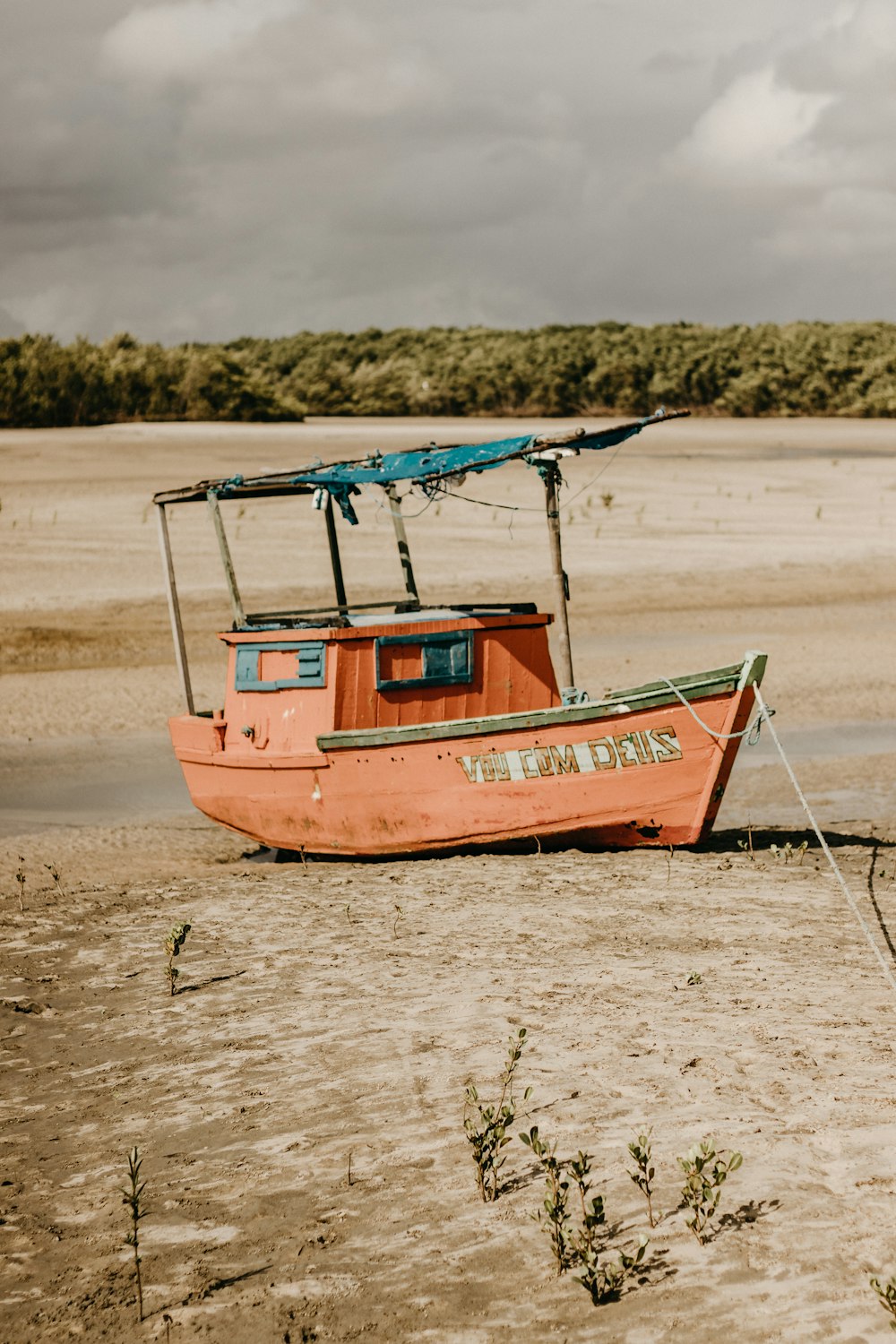 Una barca arancione seduta sulla cima di una spiaggia sabbiosa