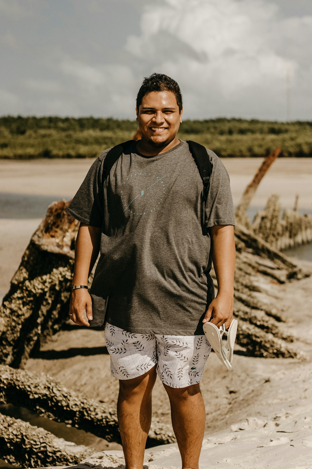 Un uomo in piedi su una spiaggia con uno zaino sulla schiena