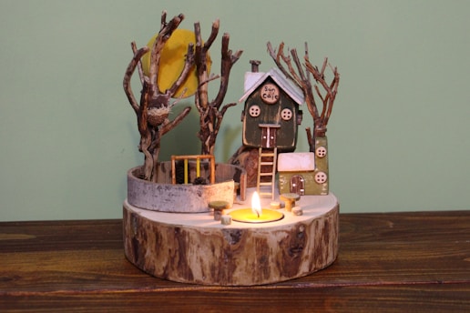 a wooden table topped with a candle and a house