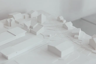 A sleek, minimalist architectural model displayed on a clean white surface with soft natural lighting.