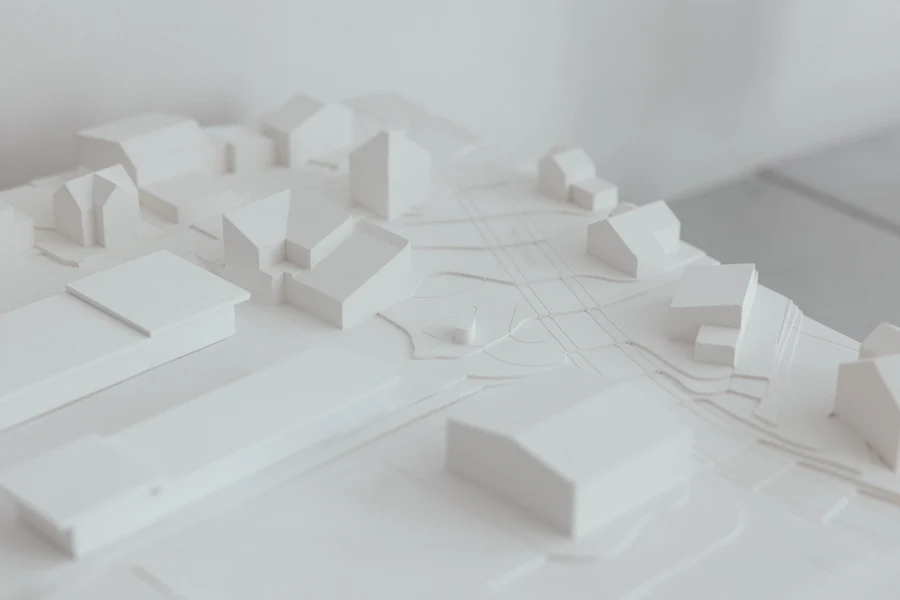A white massing model of a district, blocks and street lines across a pale board.
