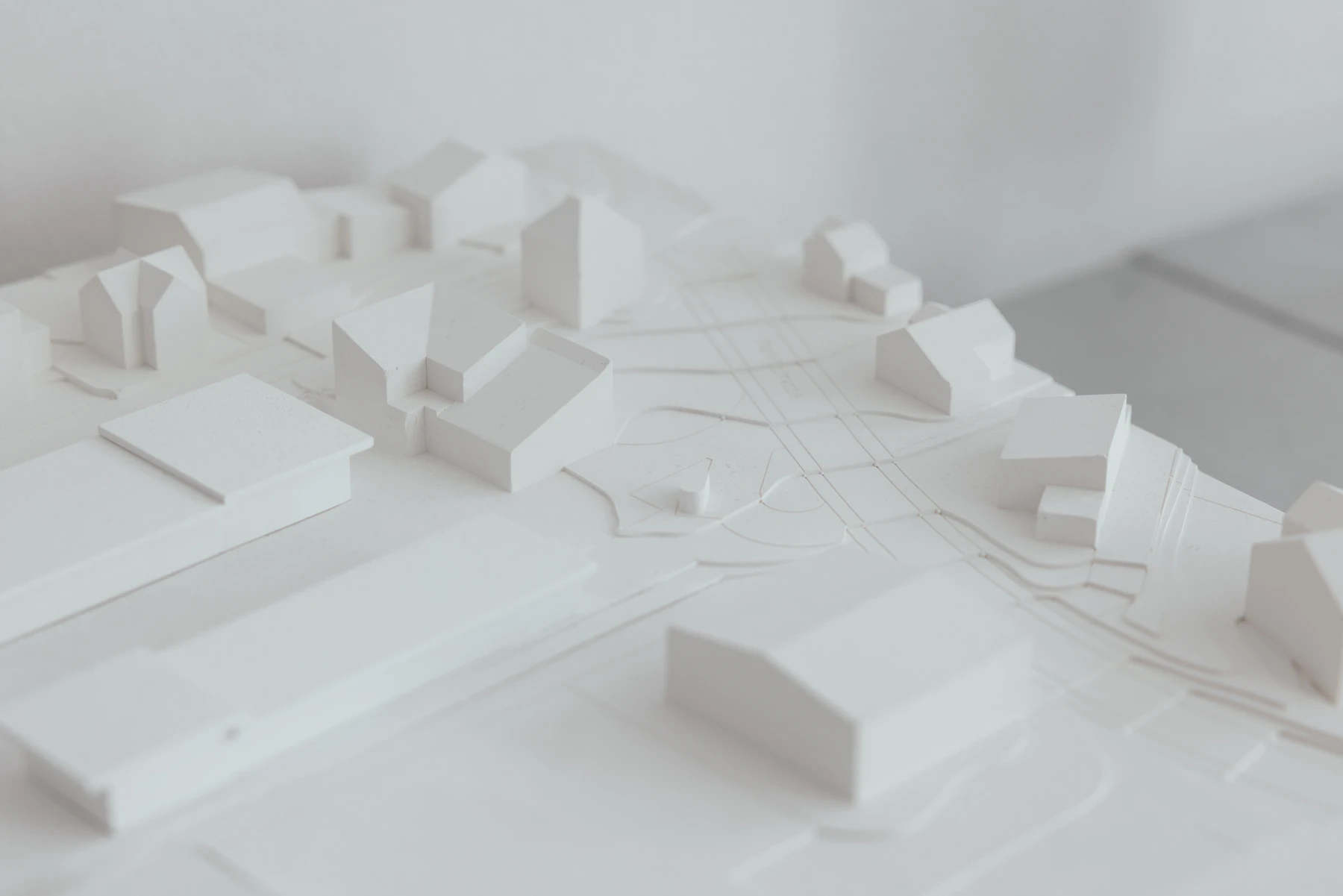 An all-white site model of plain block buildings along streets, seen from above