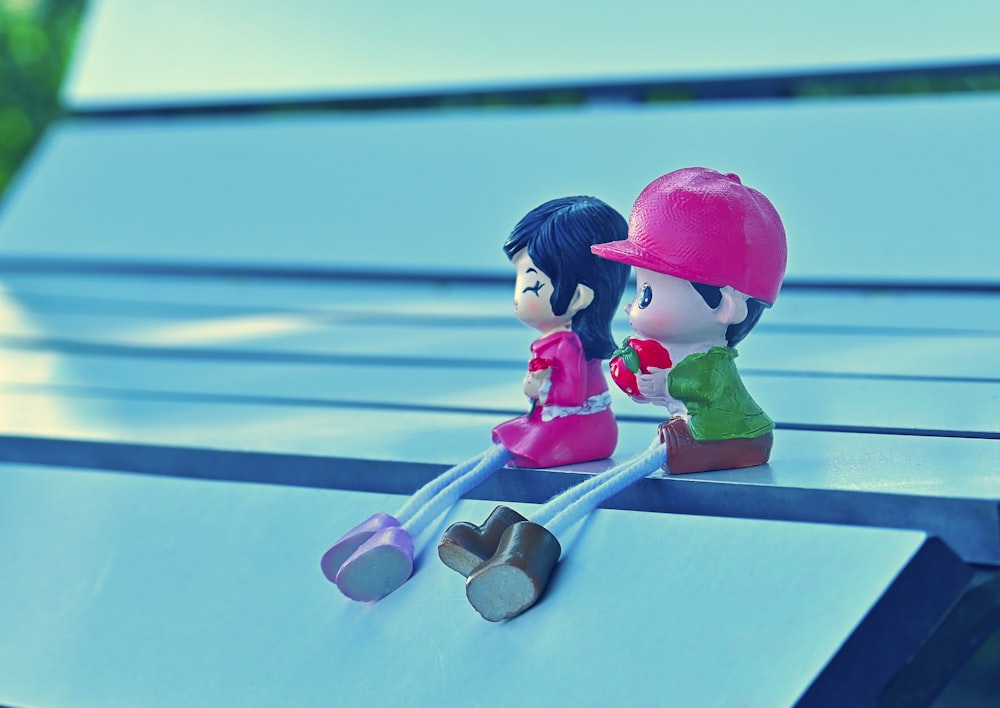 a couple of small figurines sitting on top of a wooden bench