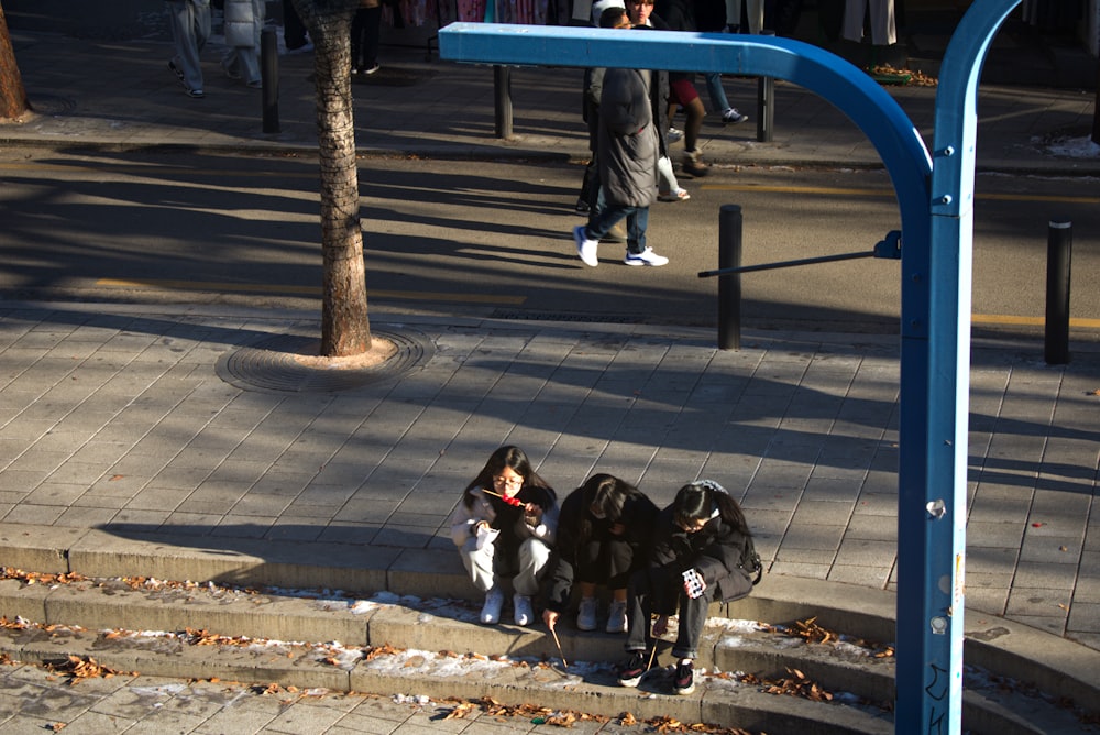 a group of people sitting on the side of a street