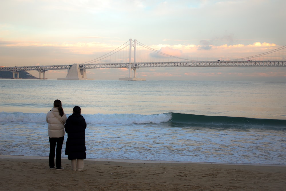 a couple of women standing on top of a sandy beach