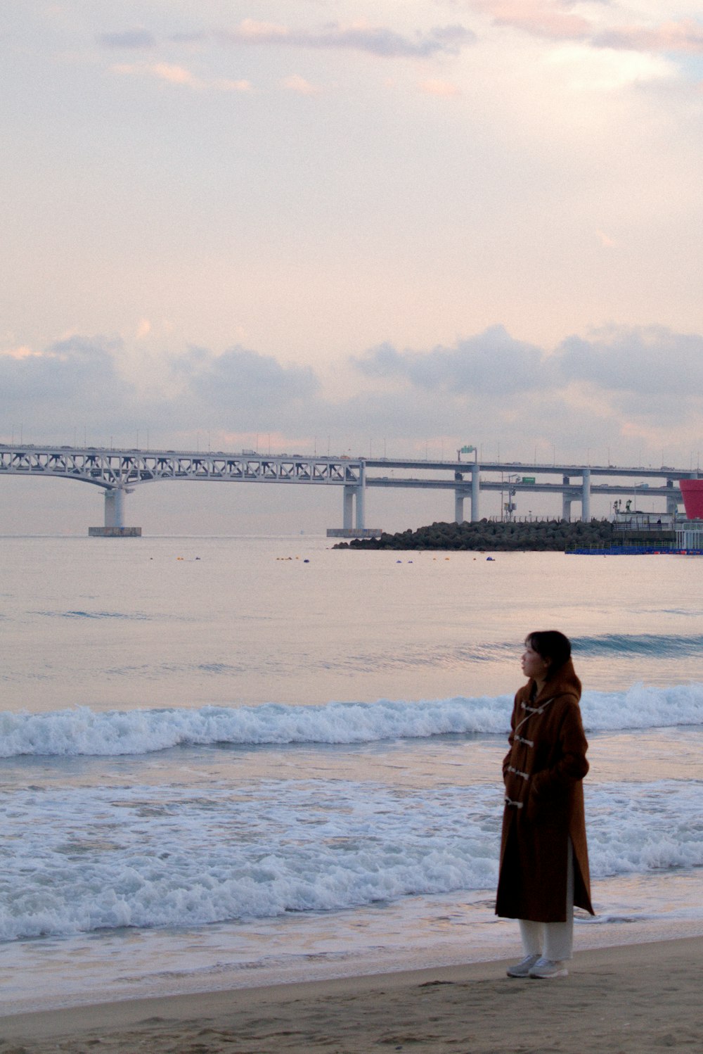 a woman standing on a beach next to the ocean