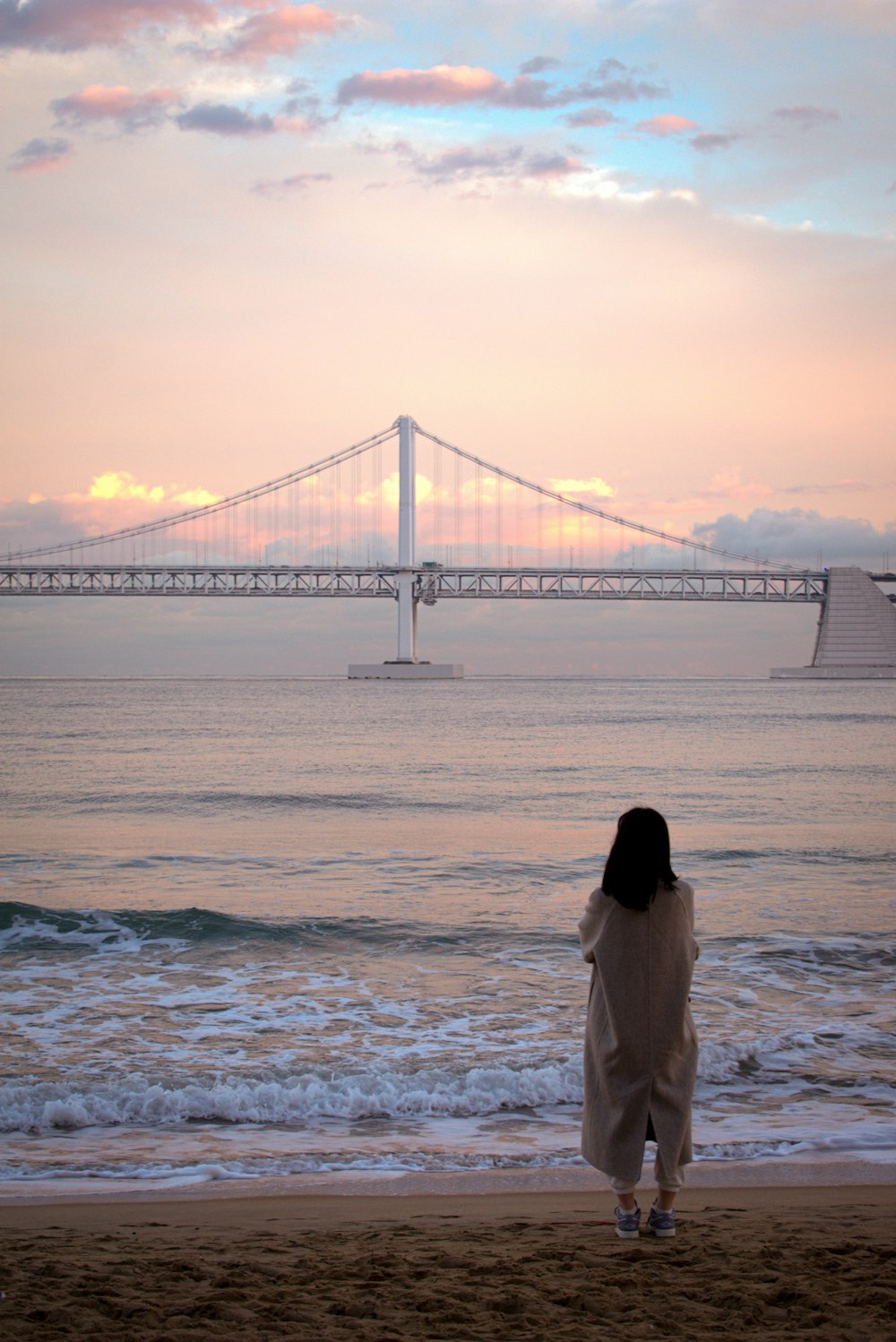 a woman standing on a beach next to the ocean