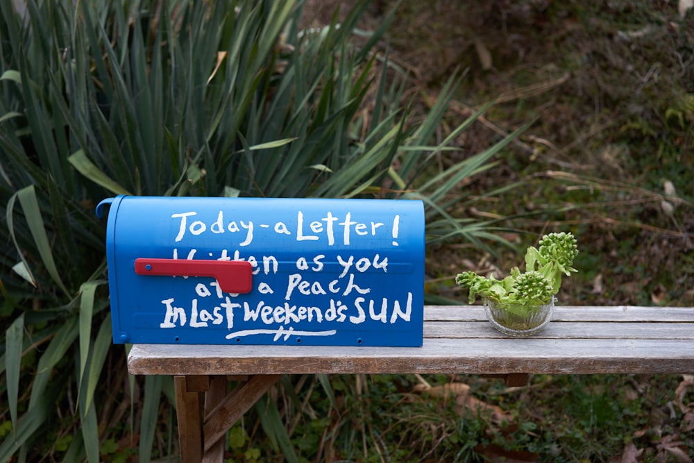 a blue mailbox sitting on top of a wooden bench