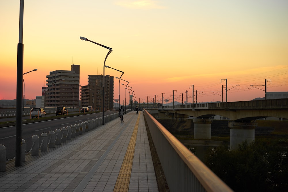 a person walking down a sidewalk next to a bridge