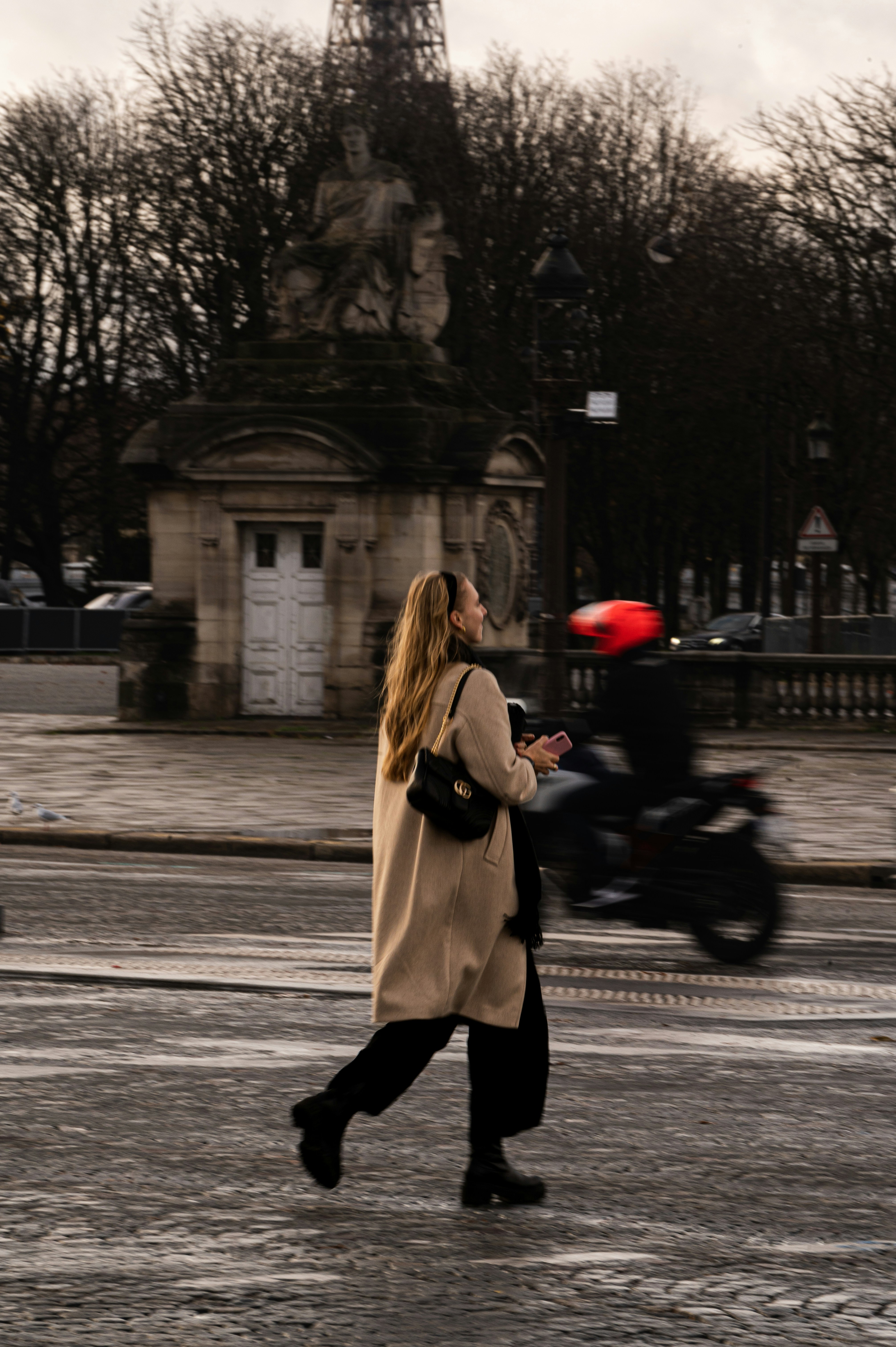 a woman walking down a street next to a clock tower