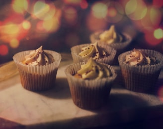 A student carefully glazing cupcakes in a bright, cozy kitchen setting.