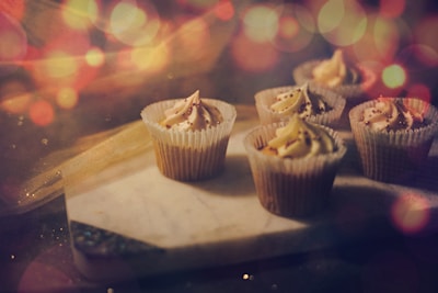 Artisan cupcakes arranged on a rustic wooden table with soft, warm tones