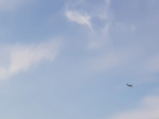 A small plane soaring above patchwork fields under a clear blue sky.