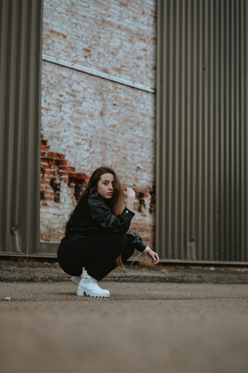 a woman squatting on the ground in front of a building